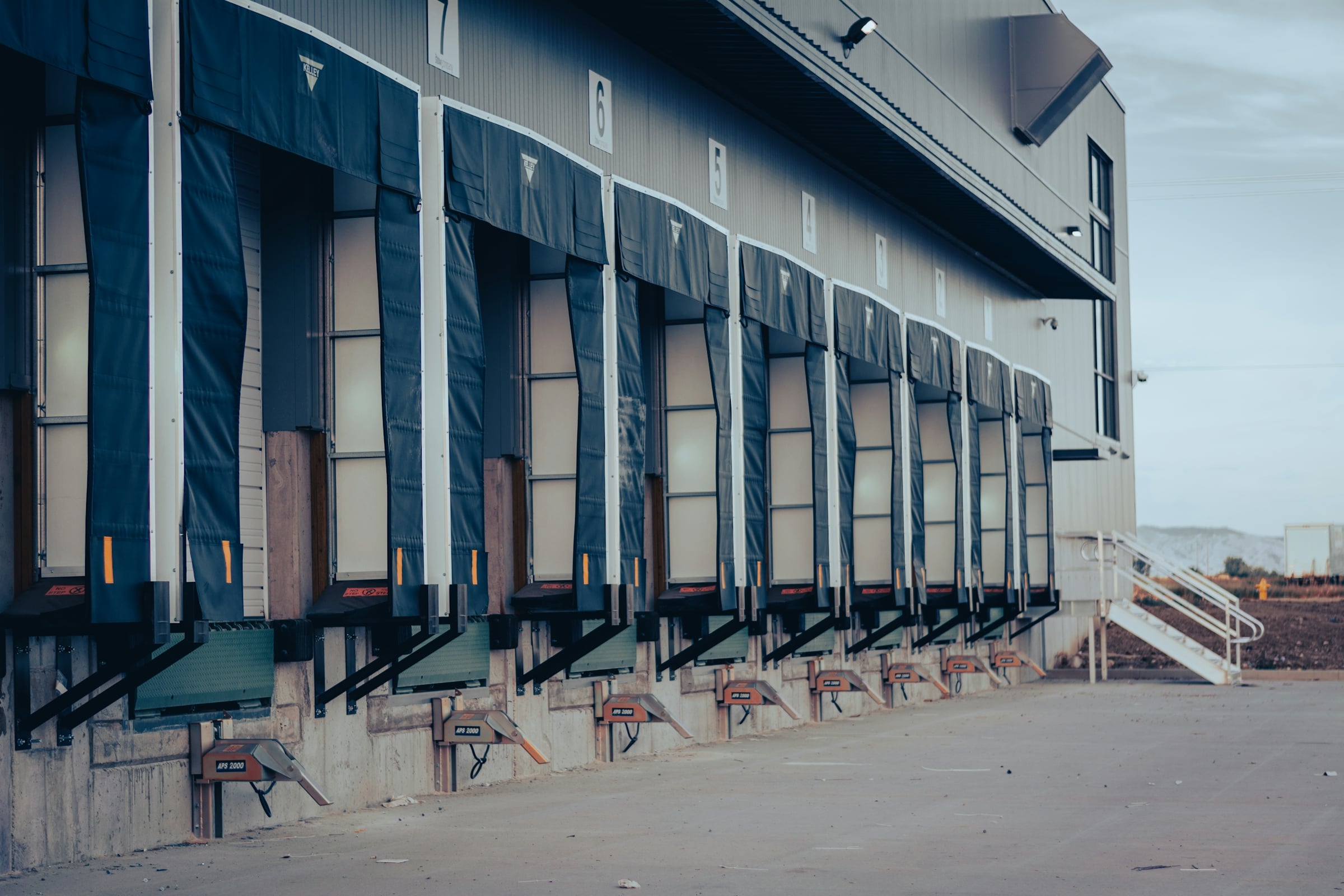 Row of loading dock bays with blue dock seals along the side of a warehouse building