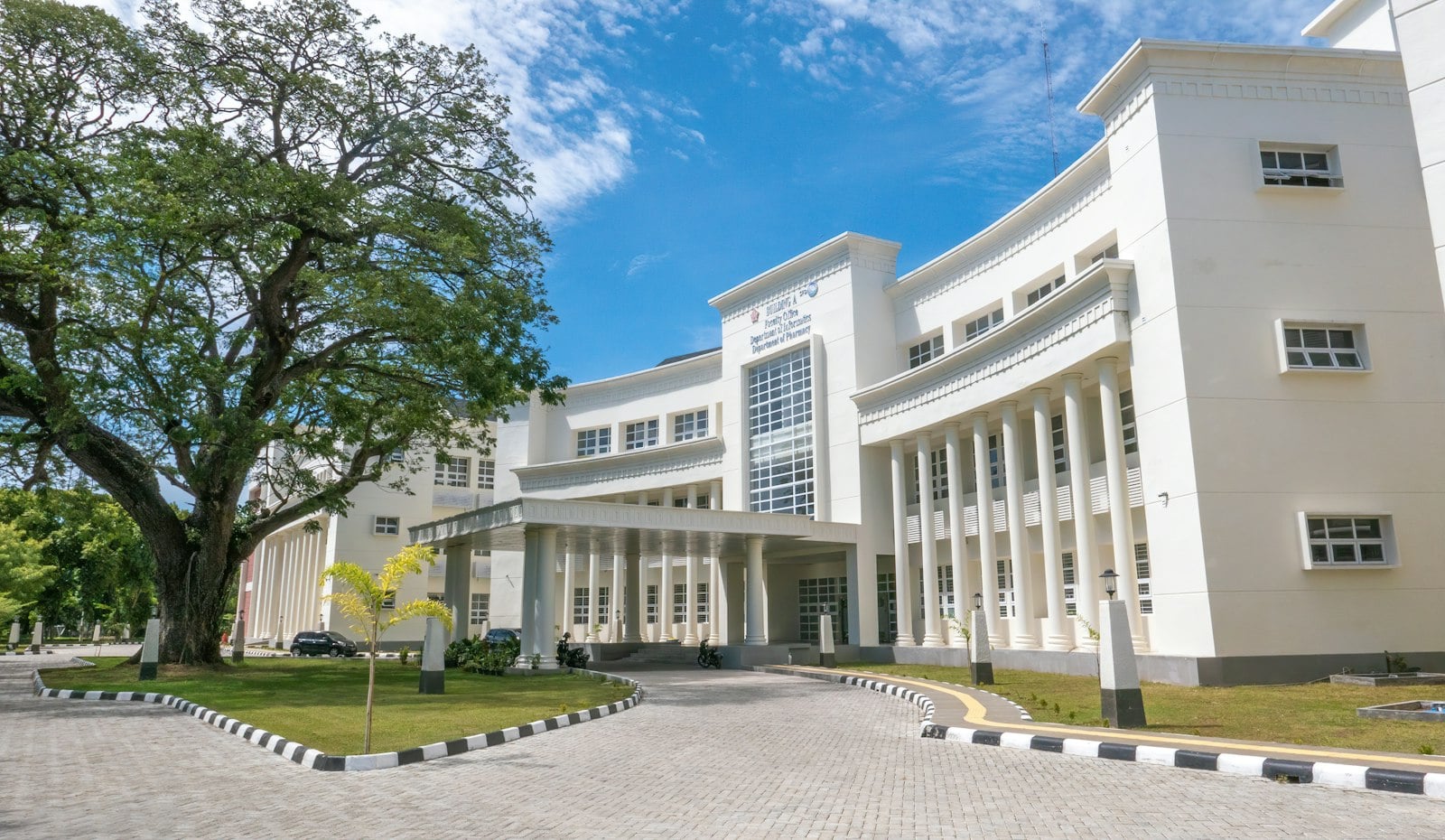 Large white school campus building with columns and a landscaped entrance drive