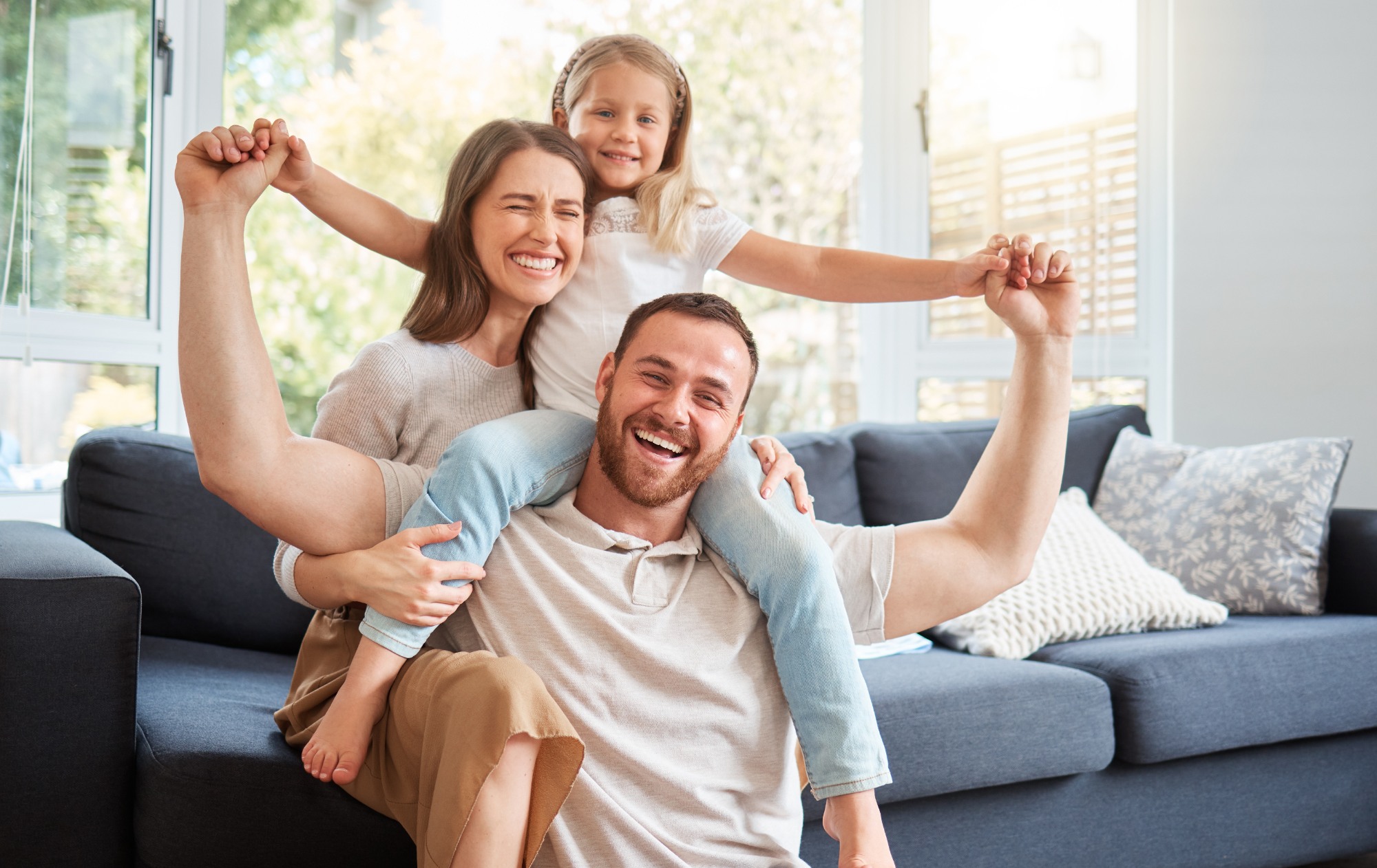 Smile, family and portrait on shoulder by sofa for weekend fun, happiness and bonding together. Playful, mom and dad with daughter in living room for support, care and love at home on fathers day