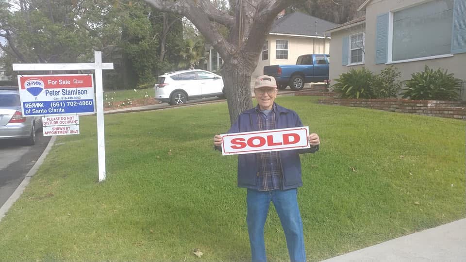 man holding sold sign