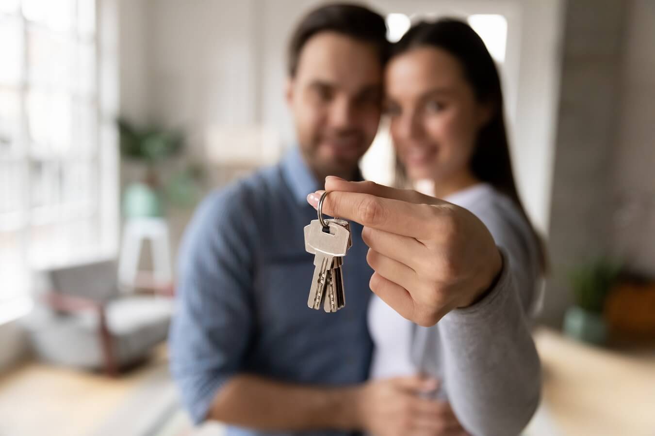Focus on keys, held by excited young spouses homeowners