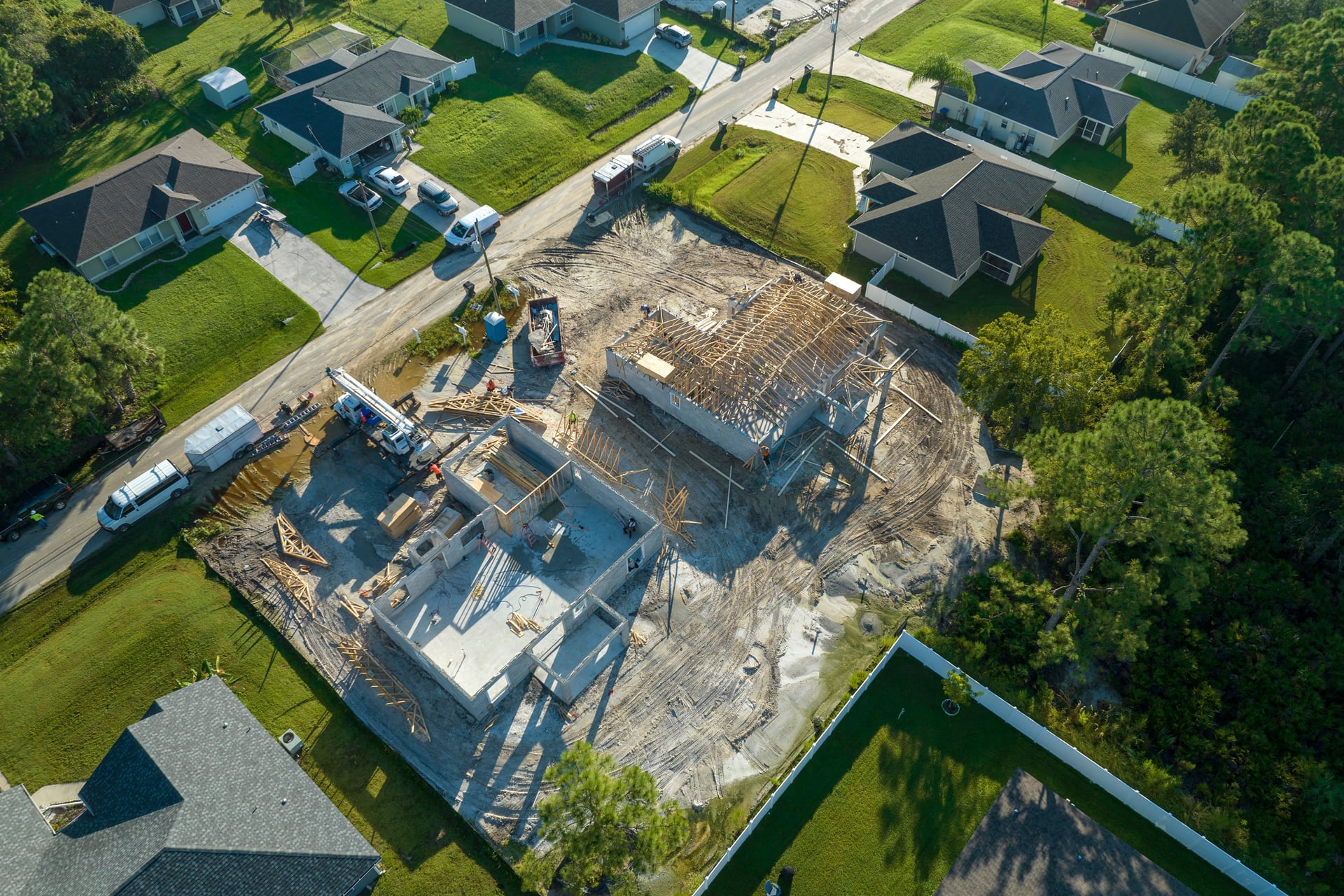 Aerial-view-of-builders-working-on-unfinished-residential-house-with-wooden-roof-frame-structure-under-construction-in-Florida-suburban-area