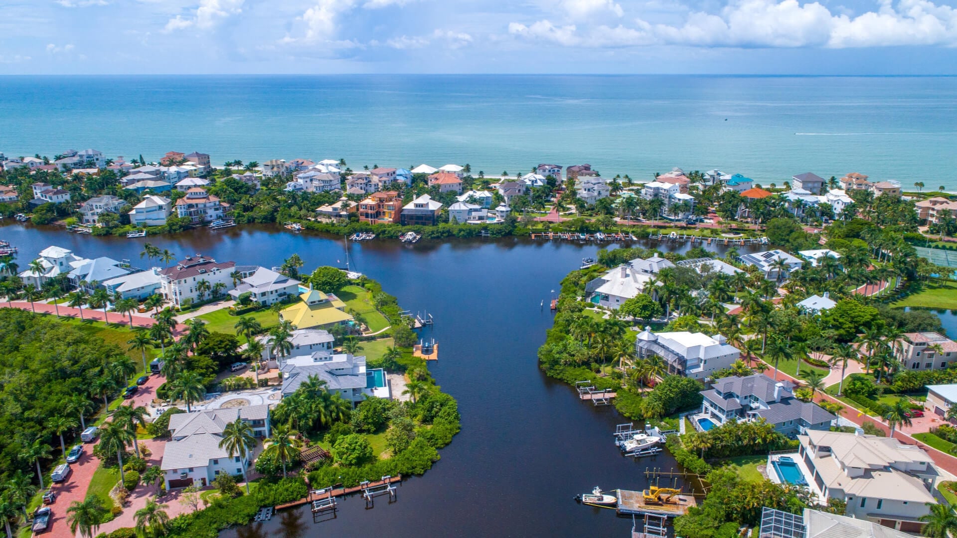 Bonita Springs - Aerial Drone View of Homes Featuring Docks on Blue Bay Waters Surrounded by Mangroves in Bonita Springs, Florida and the Gulf of Mexico in the Background with a Clear Sky