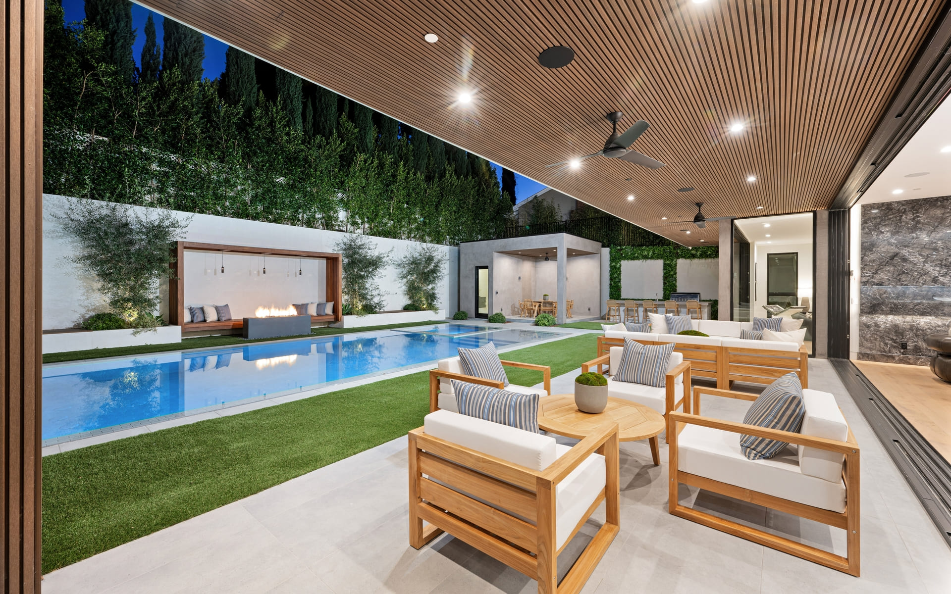 A lush green patio boasts an expansive pool and inviting seating area, New Construction Home in Tarzana, California