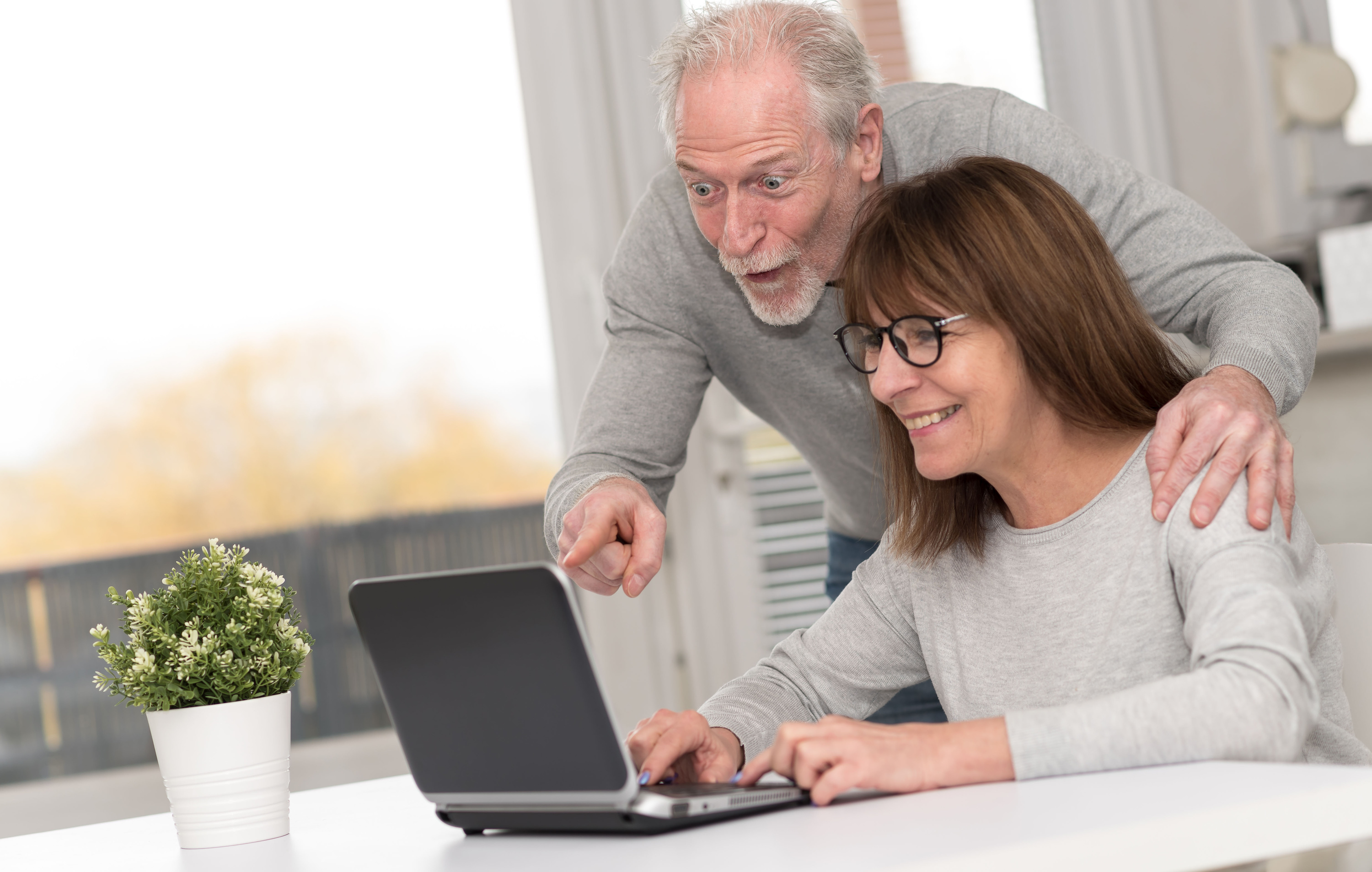 Happy mature couple having a good surprise on laptop