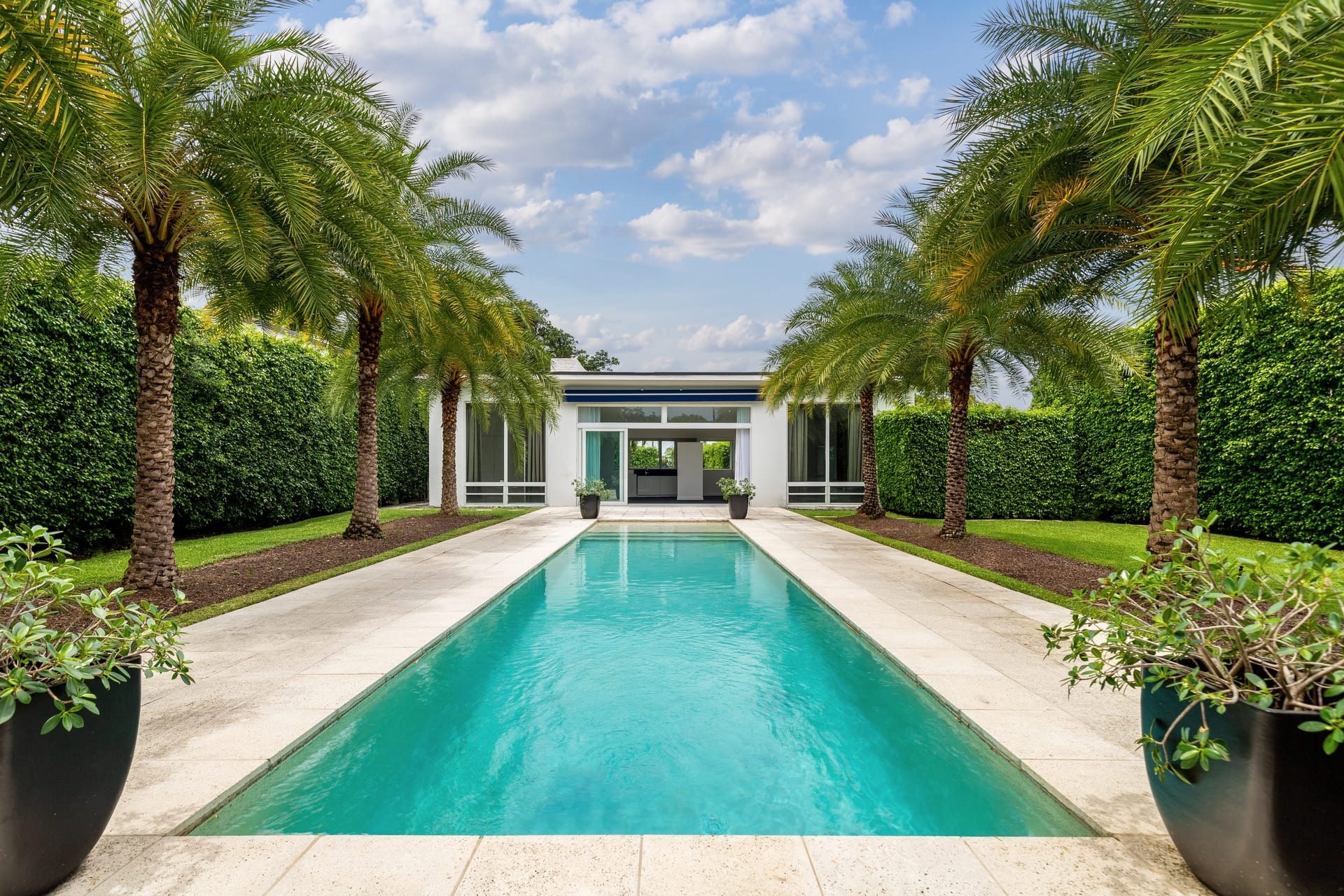Florida, USA. September Backyard of a modern house with swimming pool, artificial grass, stone path, trees, chairs and an umbrella.