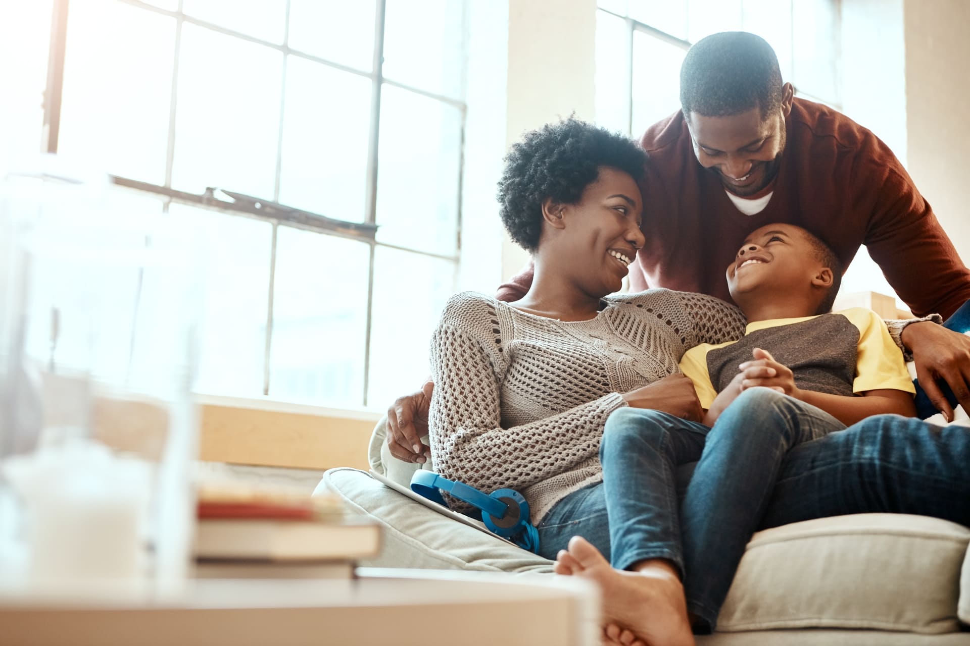 Black family, happy and relax on sofa with boy and parents, hug and laughing in their home together. Happy family, mother and father playing with their son on a couch, content and joy in living room