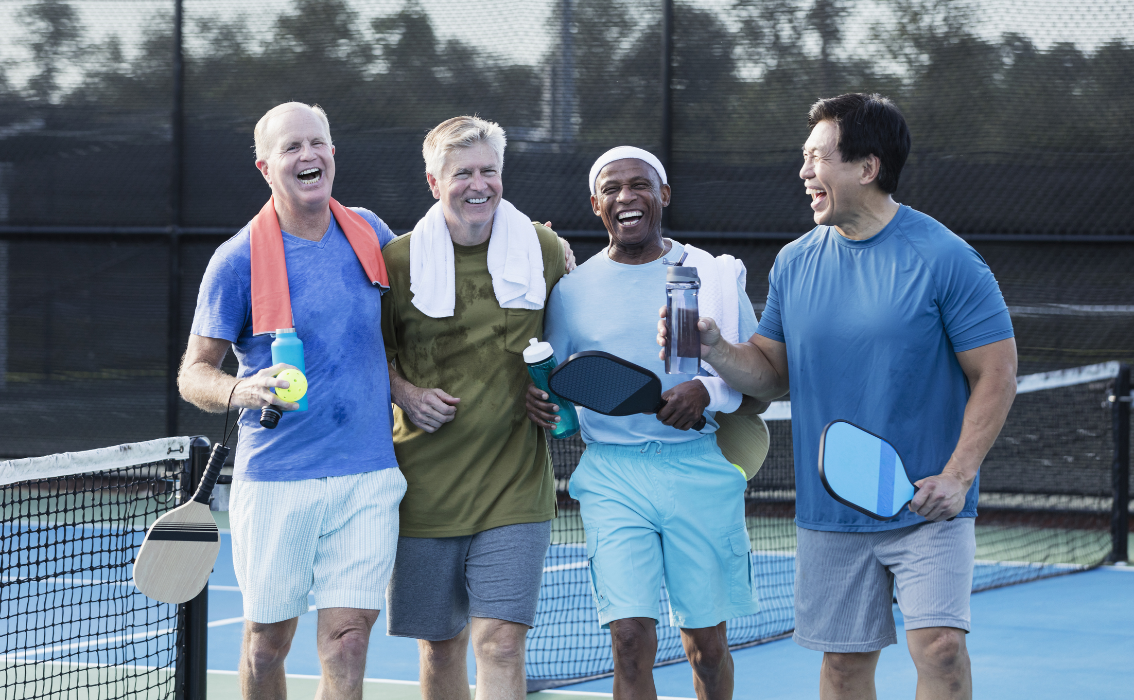 Group of senior men on pickleball court, laughing