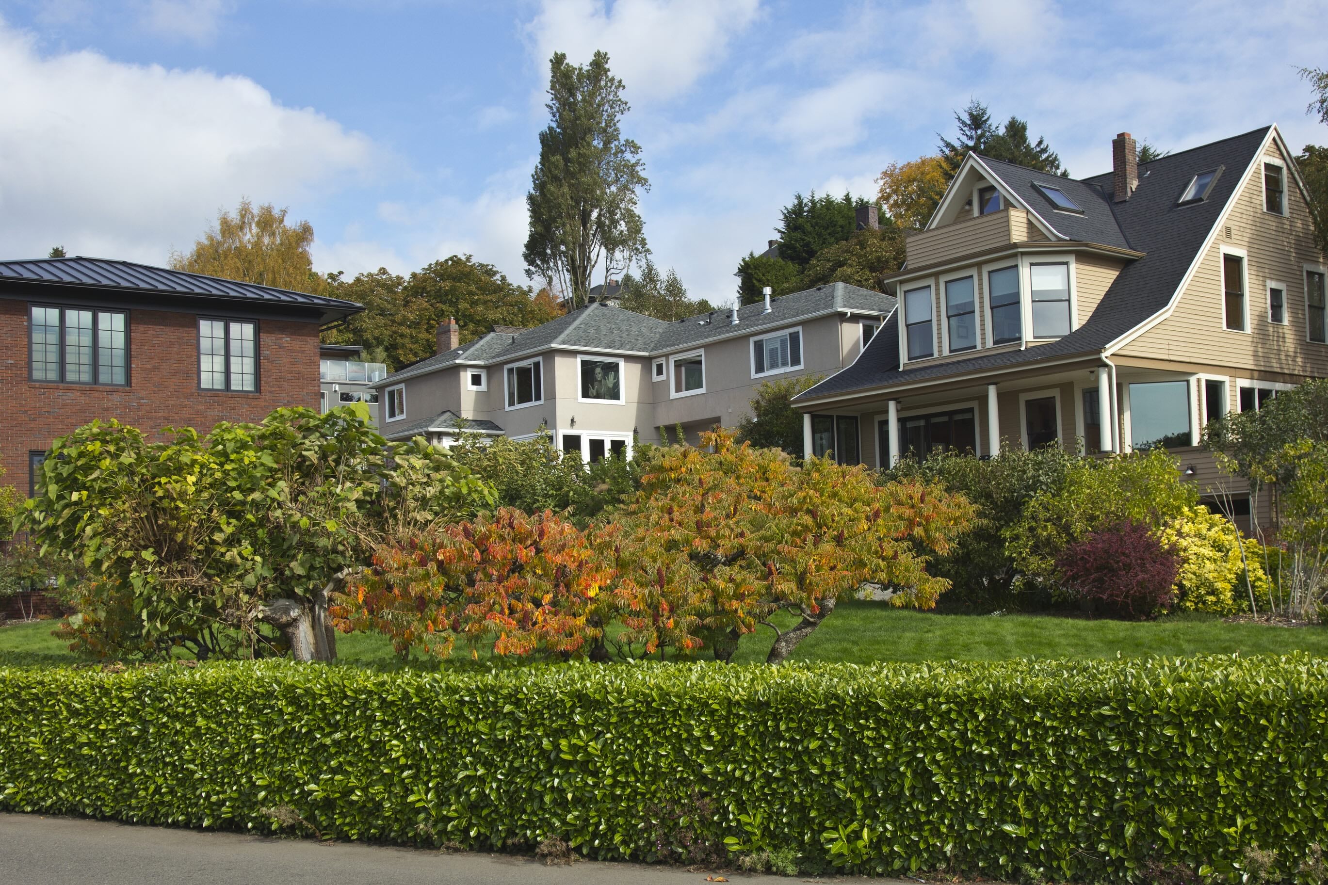 Residential homes along Highland Drive in Seattle, Washington, featuring varied architectural styles, mature trees and landscaped yards.