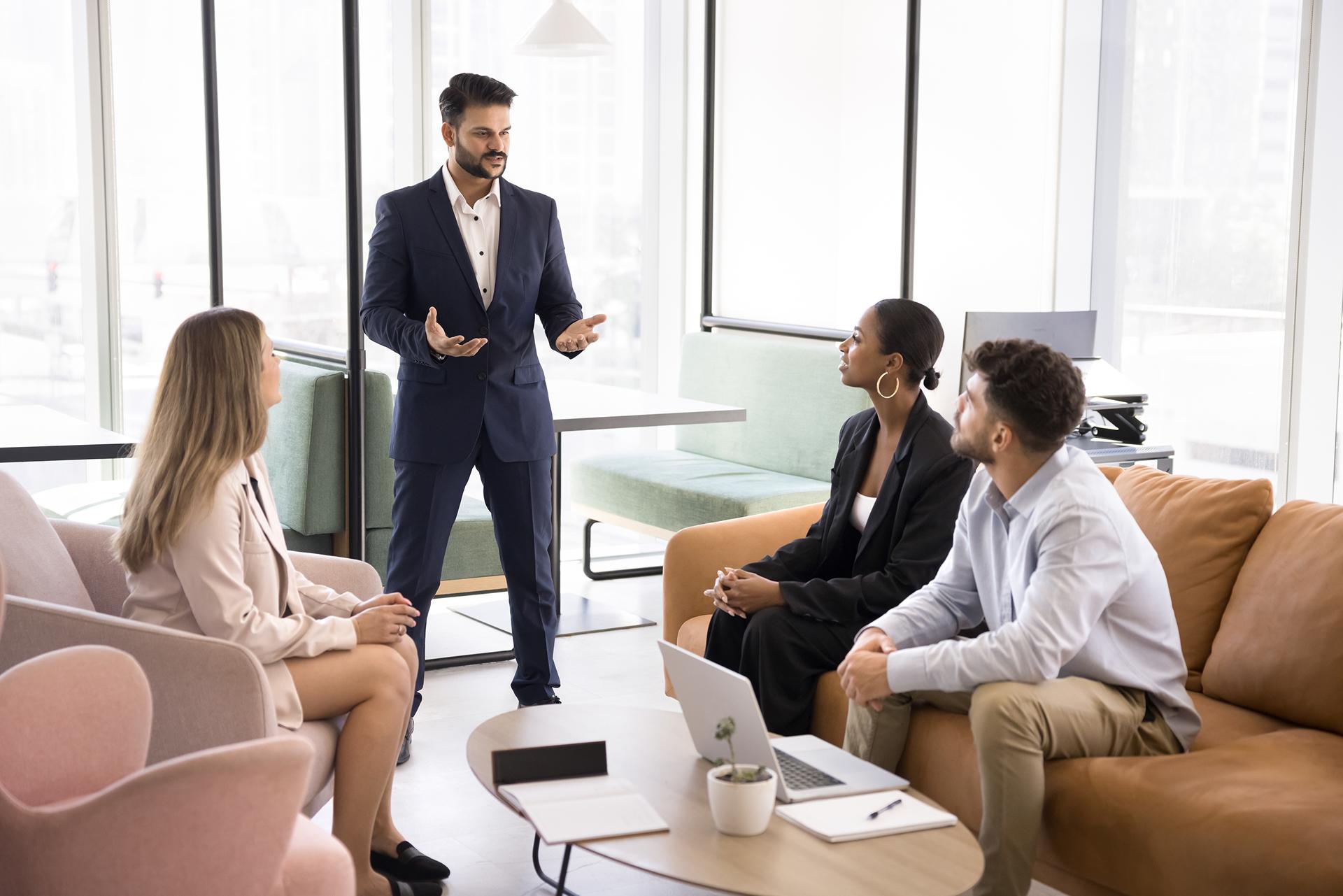 Ambitious confident young boss talking to diverse team of project managers, explaining work plan, marketing strategy, instructing employees, standing in office co-working space (1) 1 (1)
