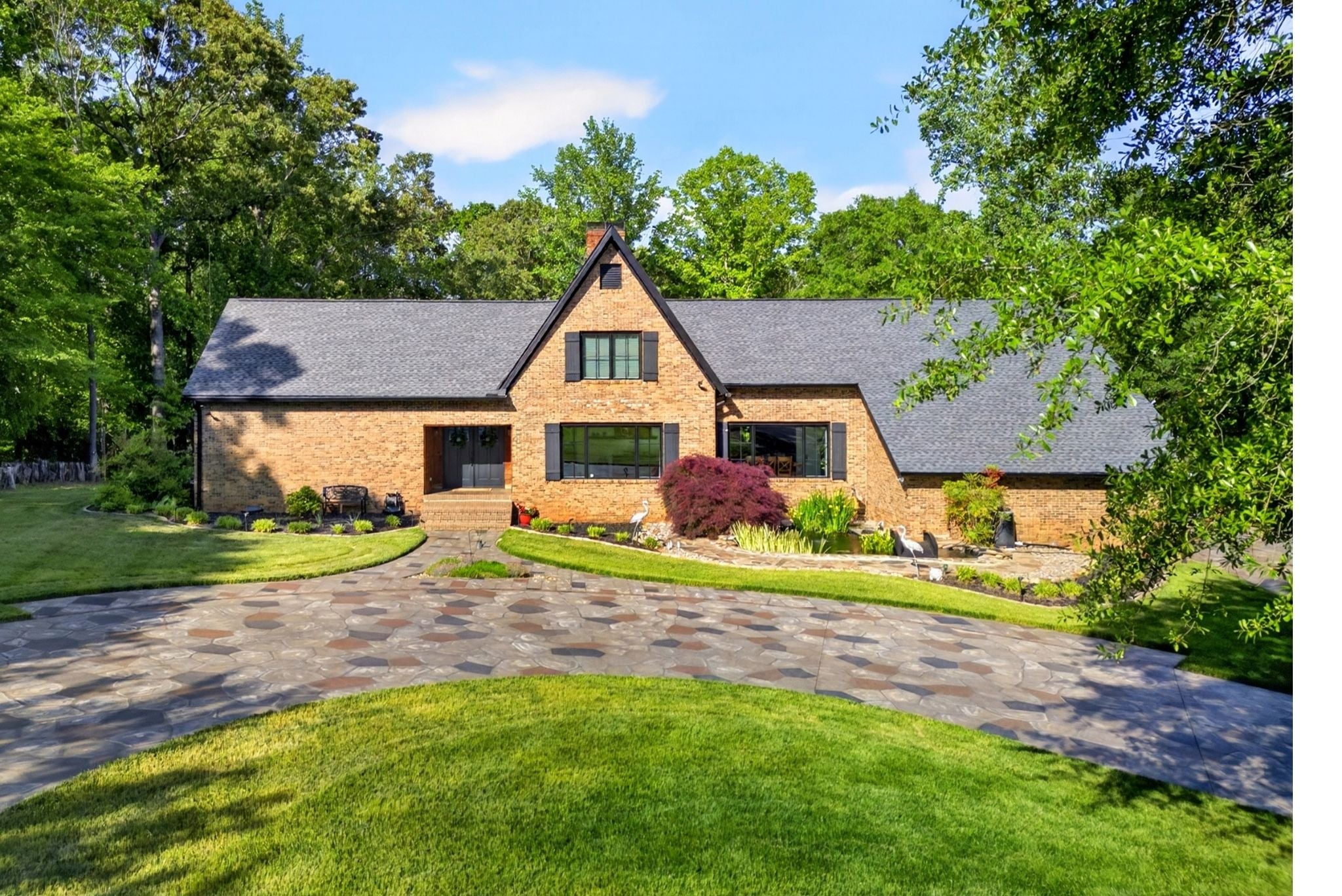 Front exterior of 106 Riverbank Ct in Moore SC featuring a brick home, landscaped yard, and circular stone driveway