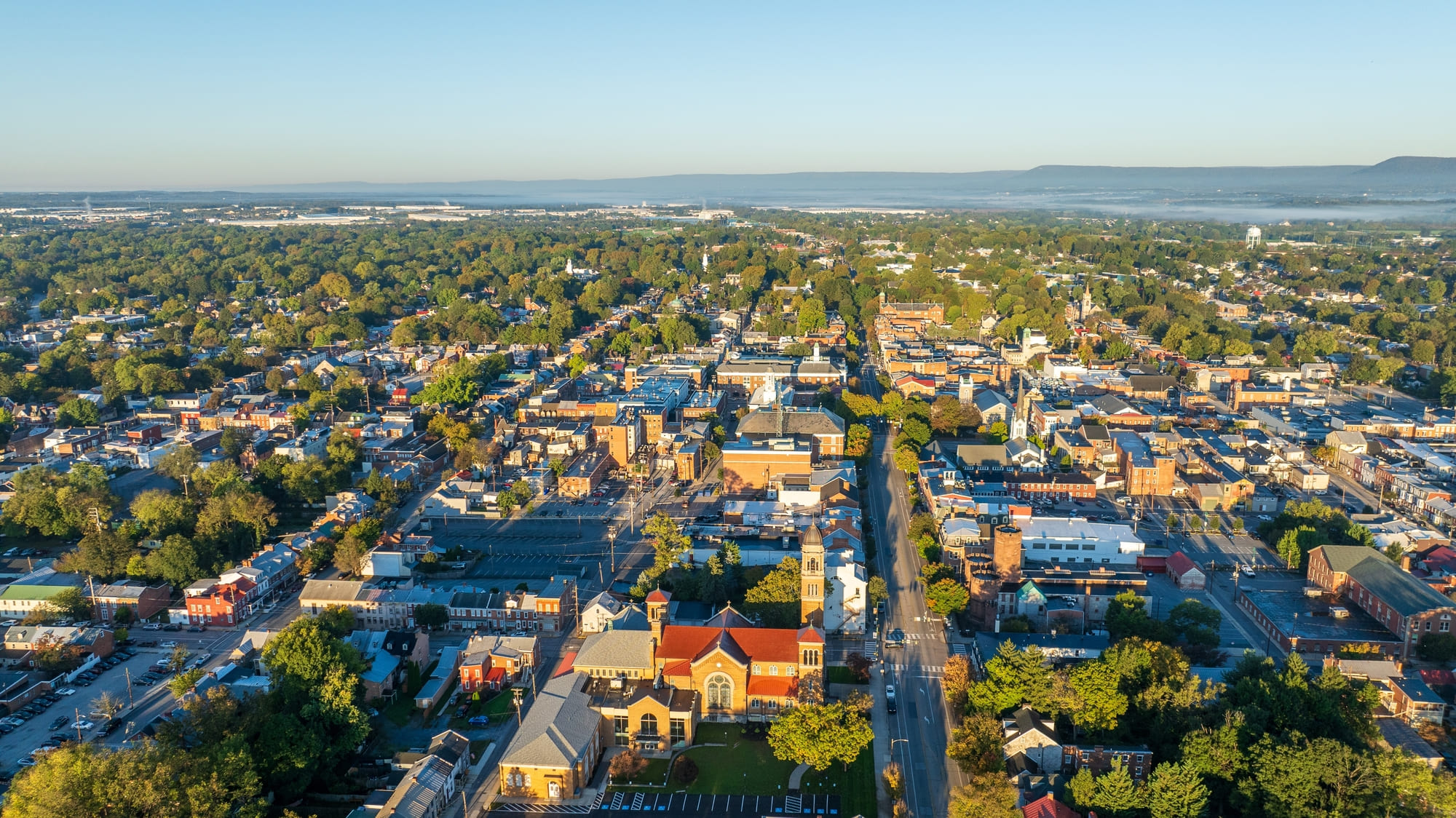 Aerial view of Carlisle, Pennsylvania, featuring a mix of historic buildings, residential areas, and tree-lined streets on a clear day.