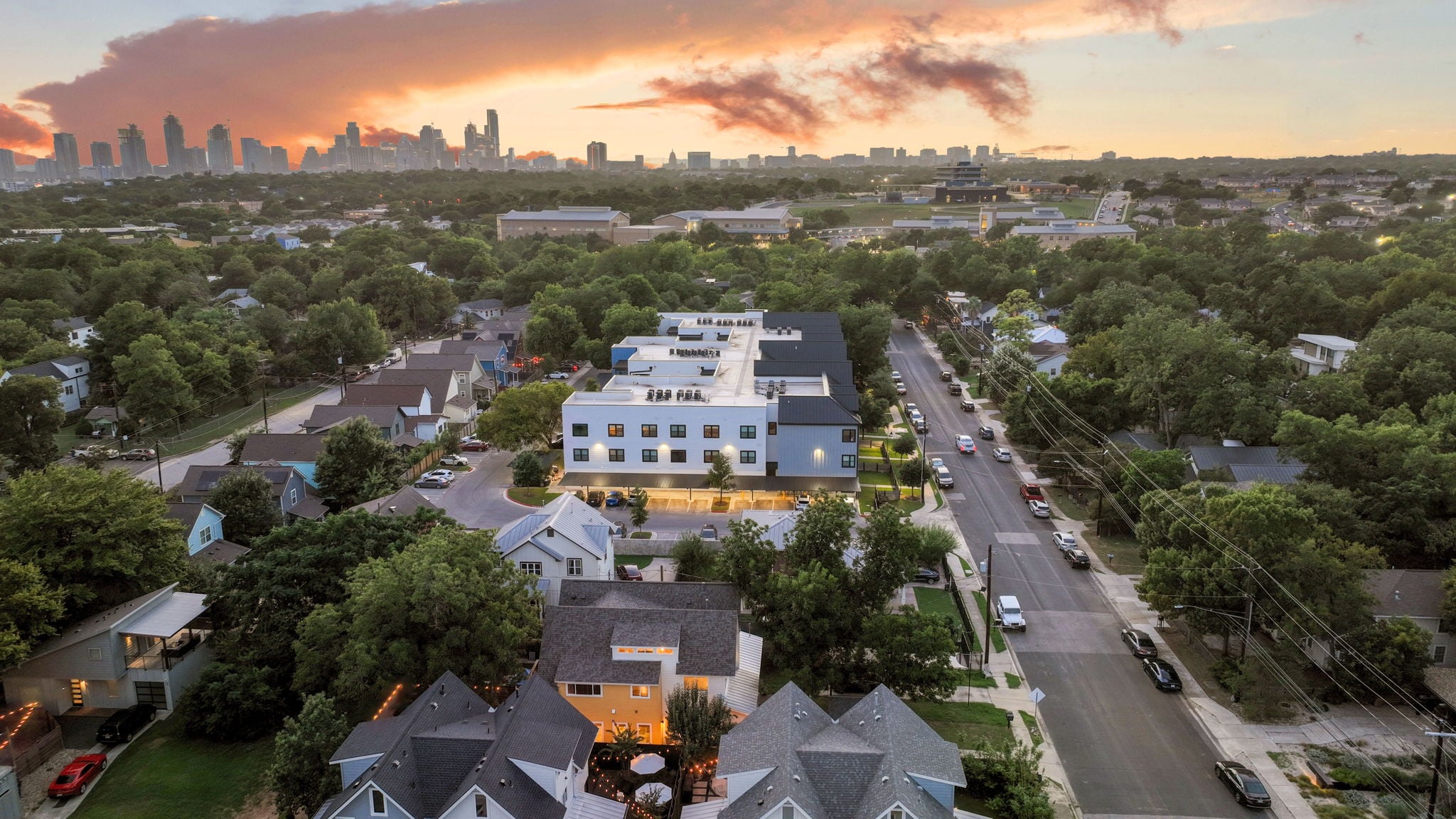 Aerial view of an Austin neighborhood at sunset with the downtown skyline in the distance