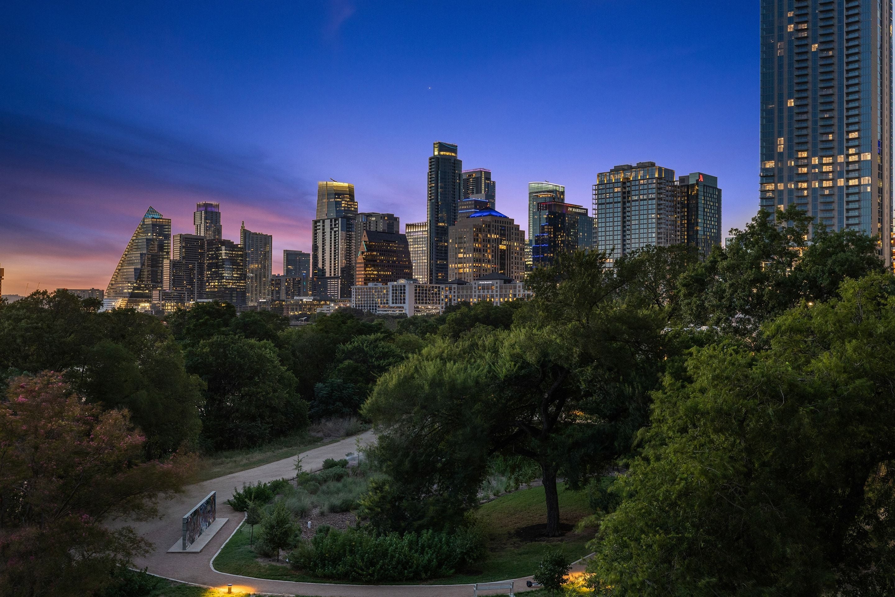 Downtown Austin skyline at dusk above the trees