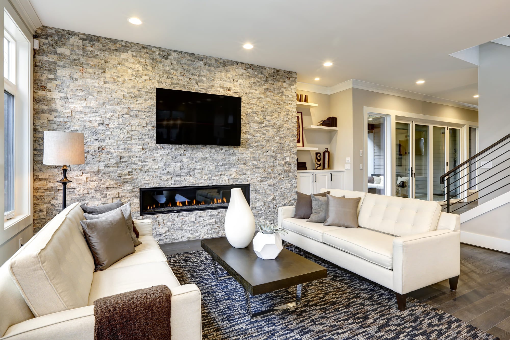 Beautiful modern living room interior with stone wall and fireplace in luxury home