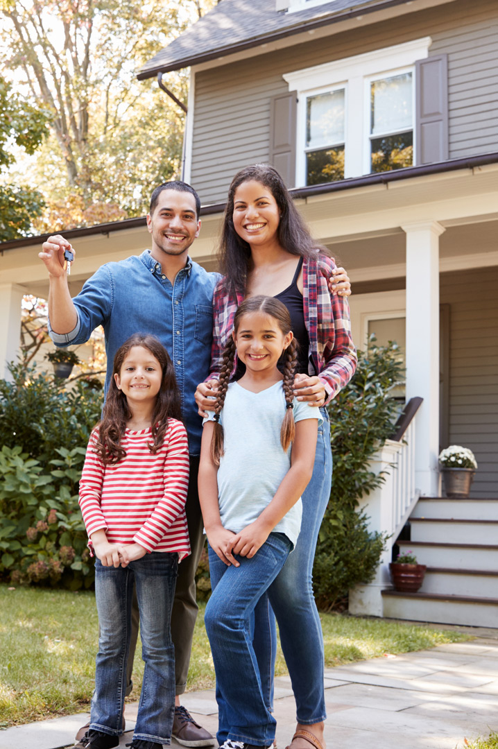 Portrait-Of-Family-Holding-Keys-To-New-Home-On-Moving-In-Day