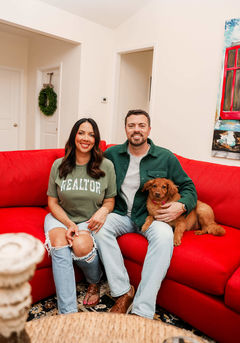 Courtney & Philip, from Britt & Co. Real Estate Professionals, team couple sitting in the sofa with their dog