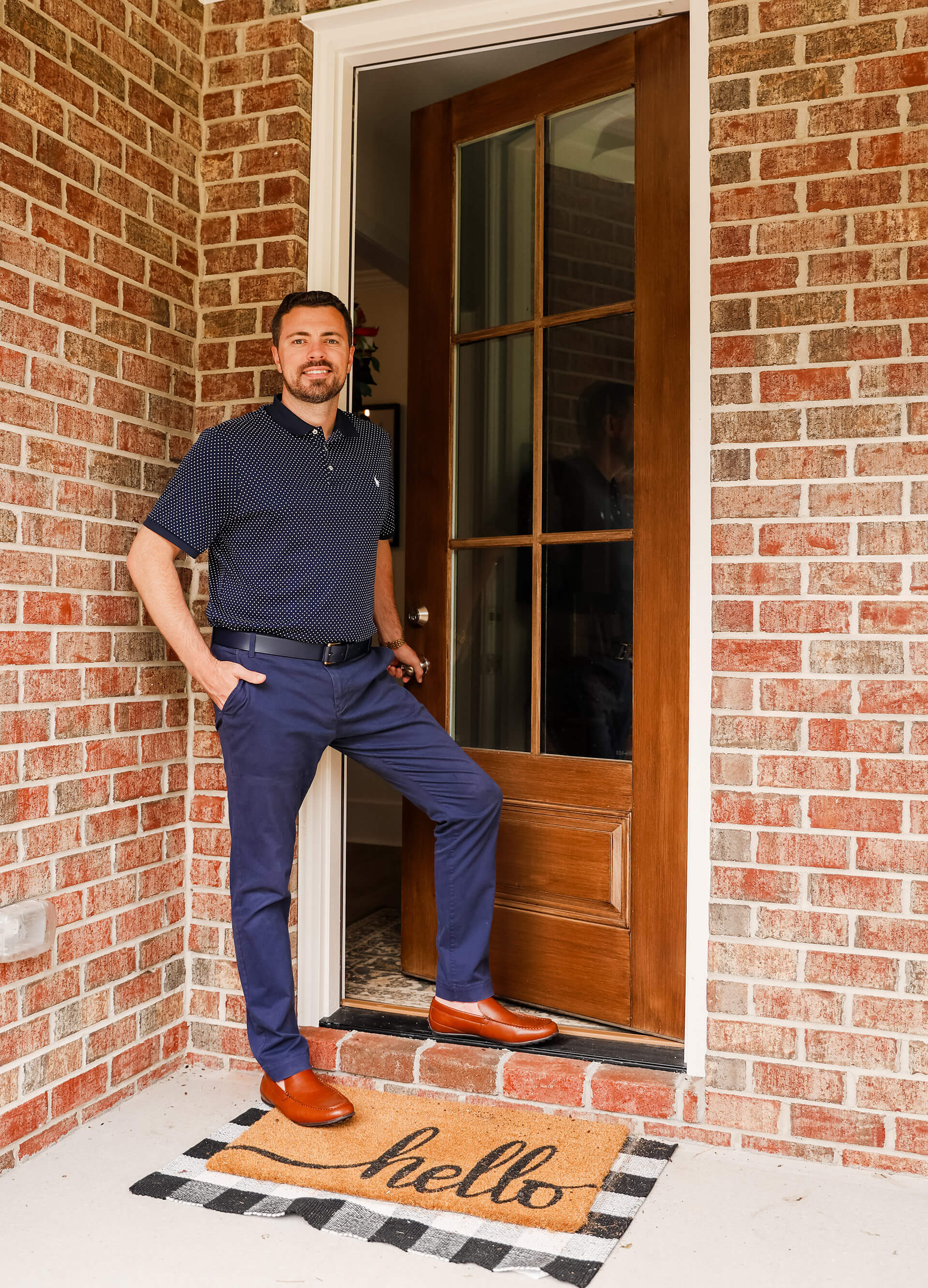 Philip, from Britt & Co. Real Estate Professionals, dress in blue at the front door of a house
