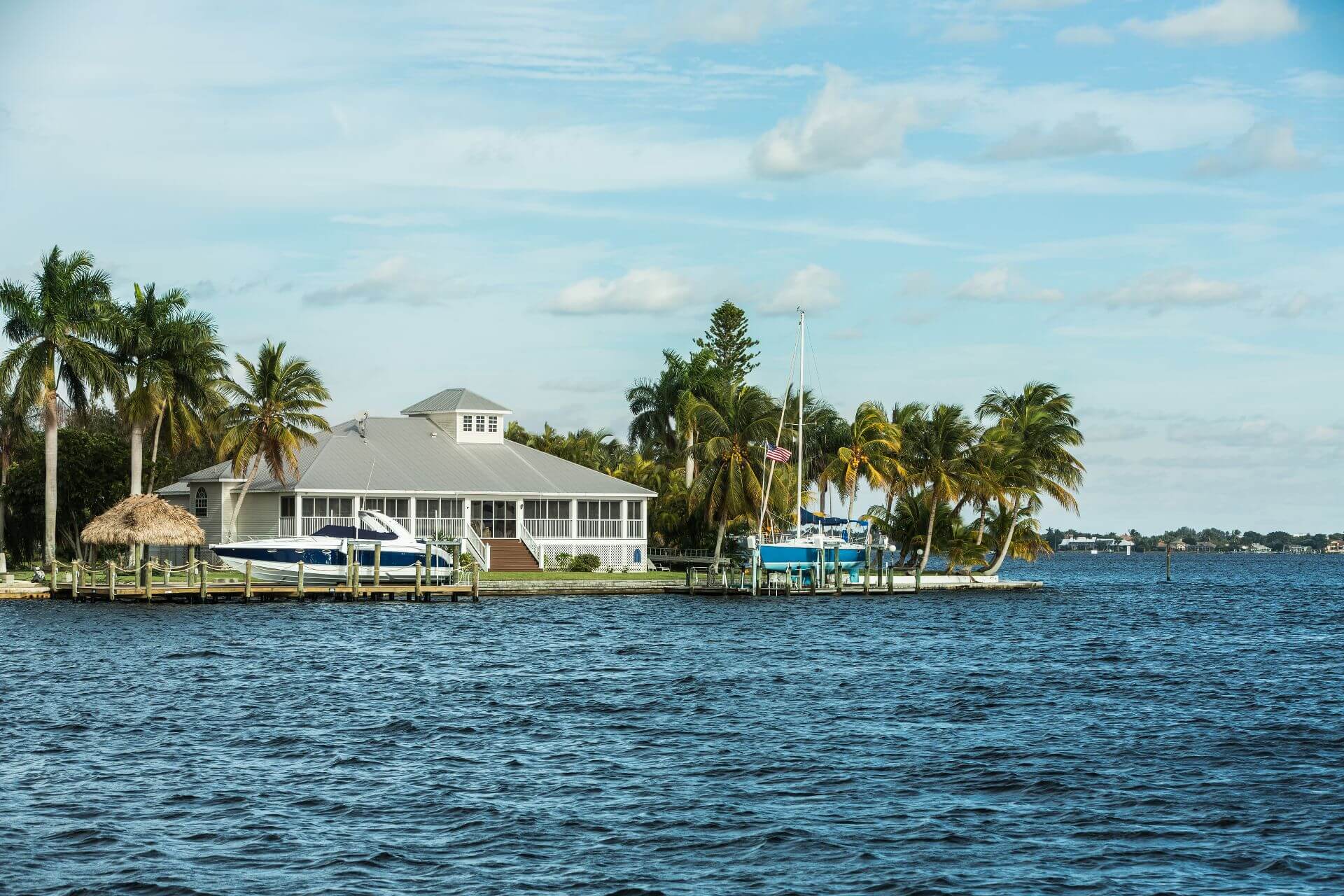 Large coastal home with a small boat tied to pier. Modern luxury waterfront real estate in Florida, USA