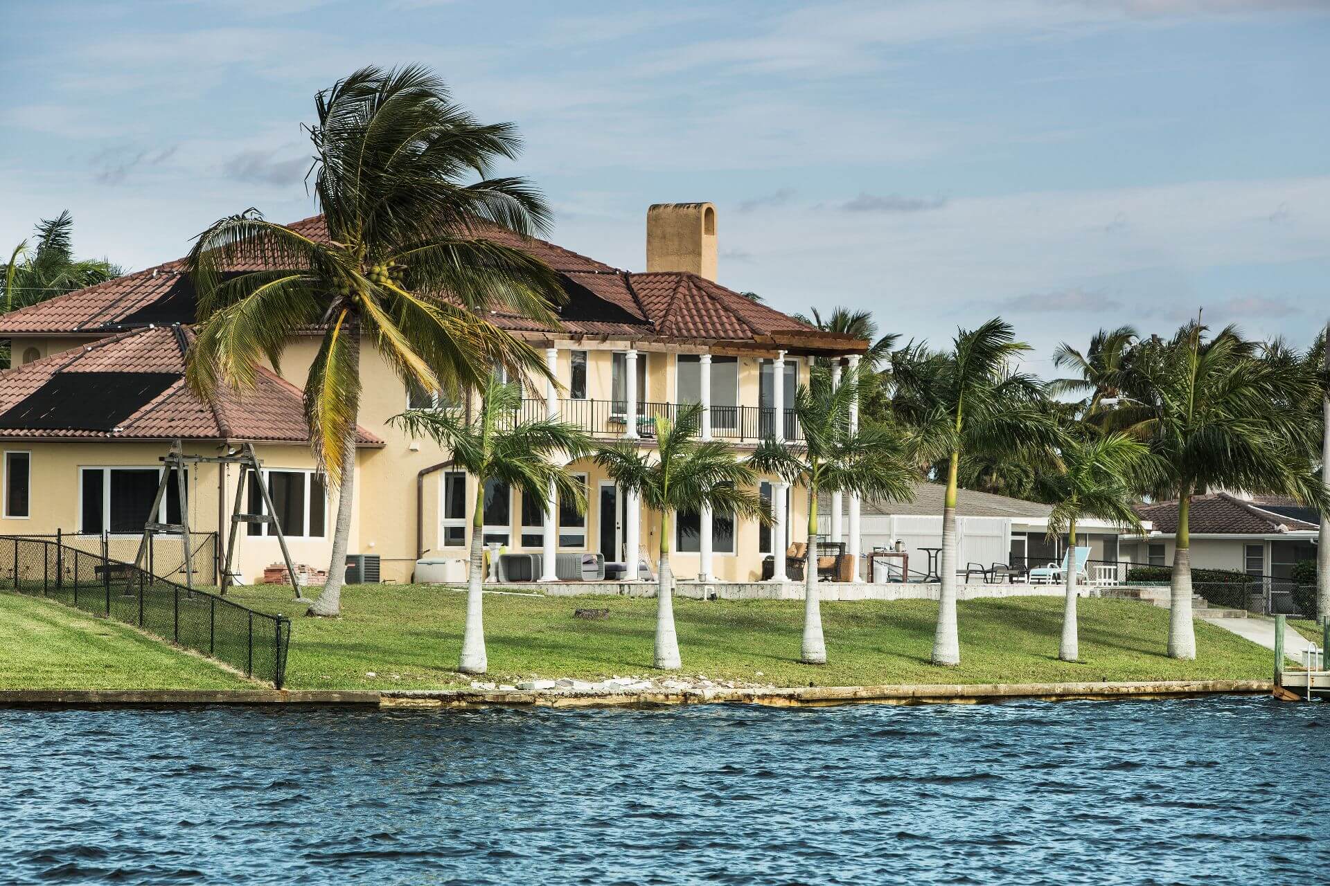 Large coastal home with a small boat tied to pier. Modern luxury waterfront real estate in Florida.