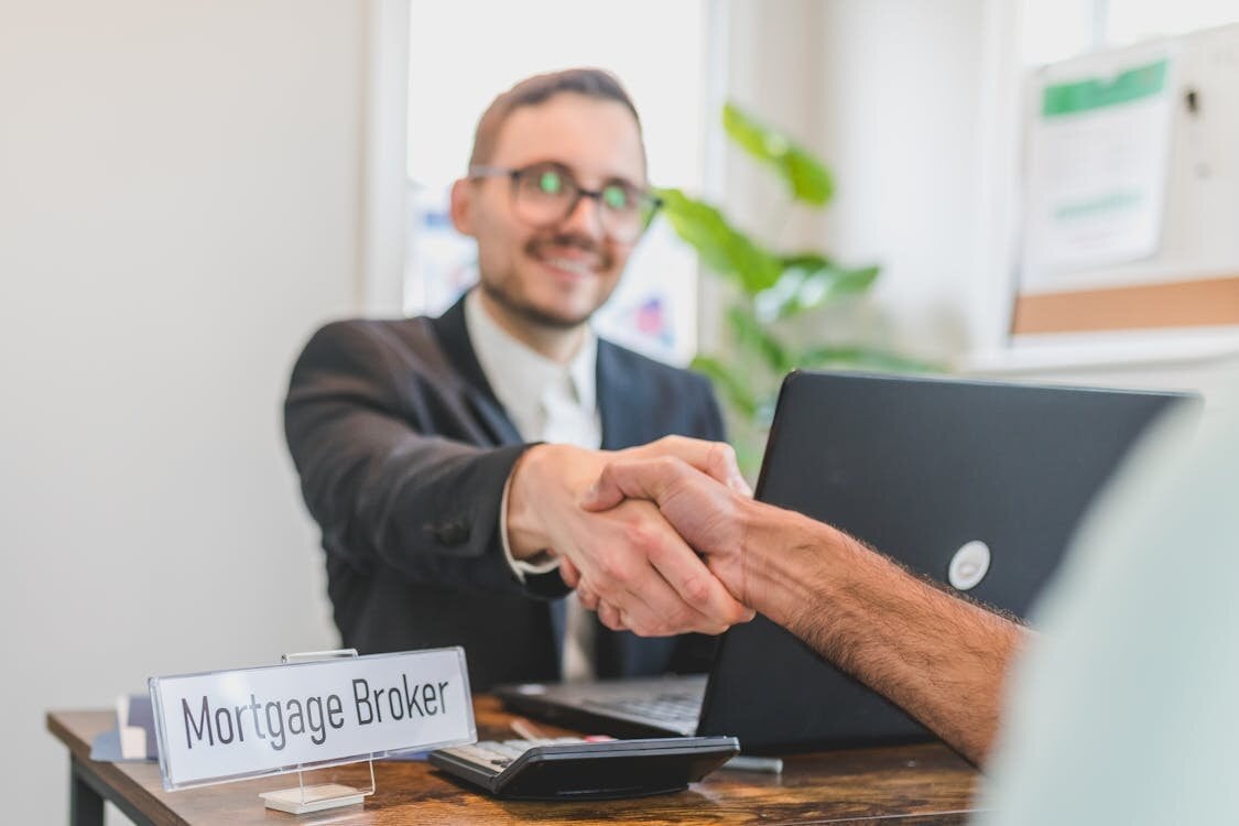 Andrea Andrews Compass Rose Realty real estate broker meeting handshake with client at office desk