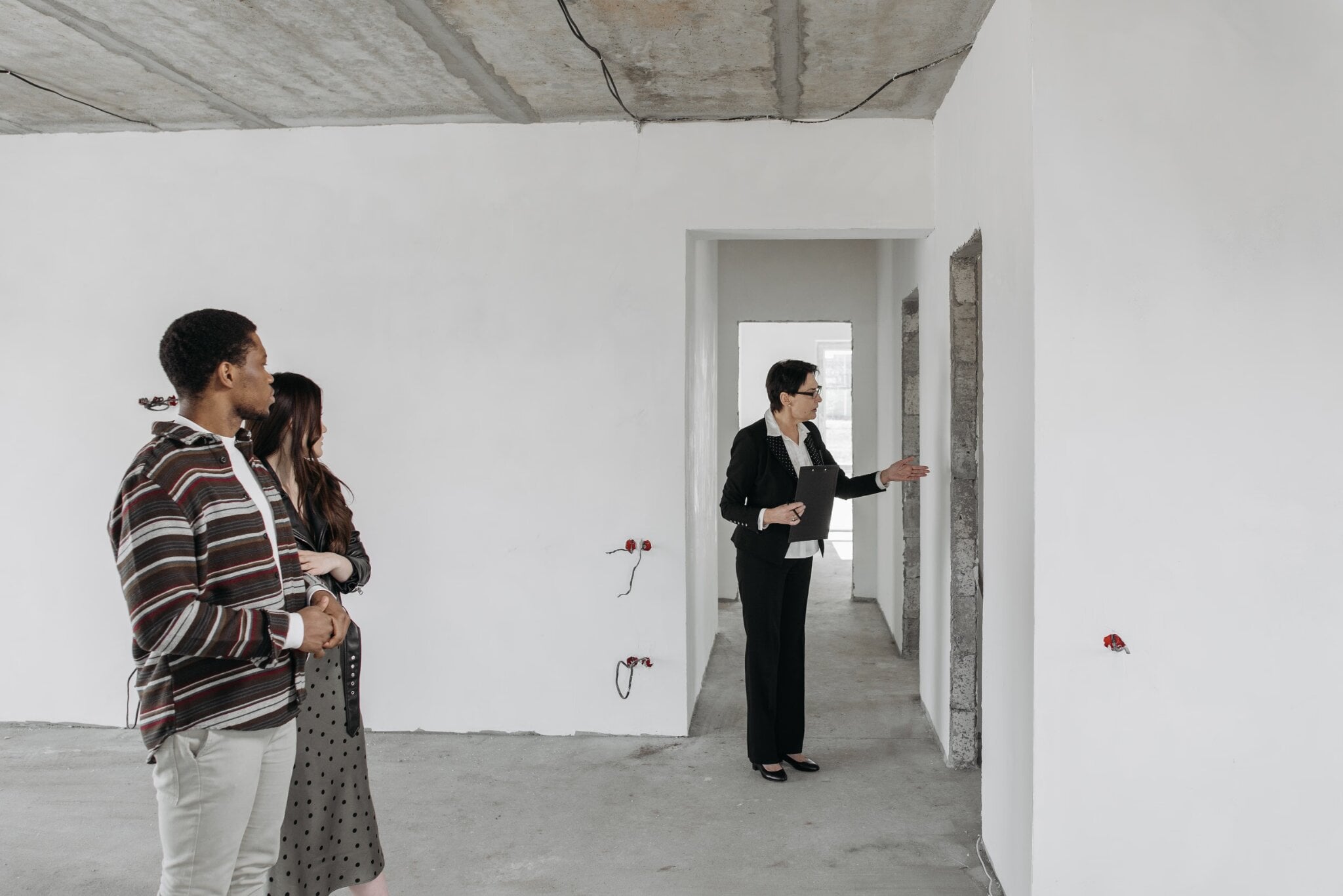 Homebuyers viewing an unfinished new construction property with a real estate professional, illustrating insights from Mike Lyon of Do You Convert.