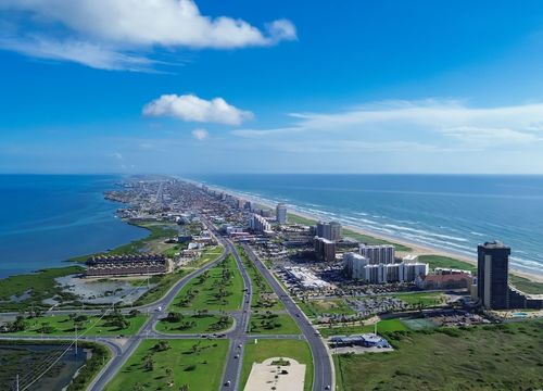 Downtown South Padre Island along Padre Boulevard, State Park Road 100 from Isla Blanca Beach, high-rise condos, beach-front hotels, white sandy beaches turquoise water, calm waves, aerial view. USA 1