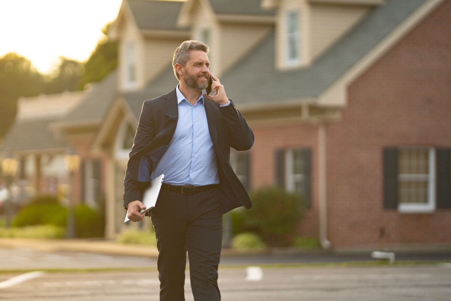 A real estate broker stands confidently outside a residential building
