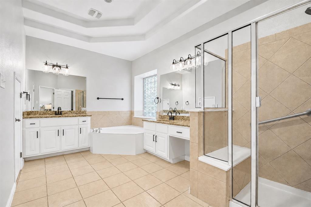 Main-level primary bathroom with dual vanities and soaking tub at 8008 Ladera Verde Dr