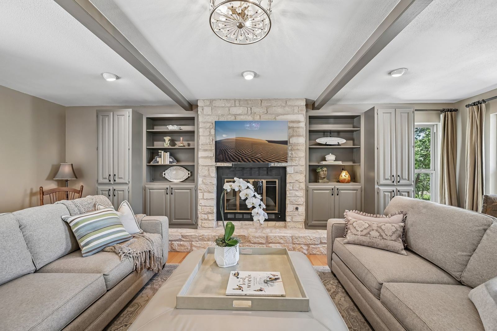 Living room with stone fireplace, built-in shelving and beamed ceiling in a Lost Creek home for sale, Austin TX