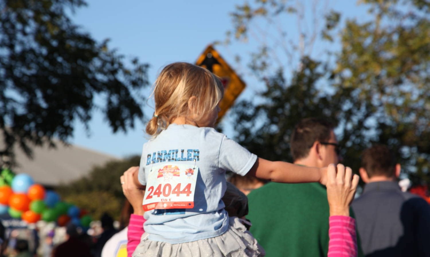 Young runner on a parent's shoulders at the ThunderCloud Subs Turkey Trot in Austin