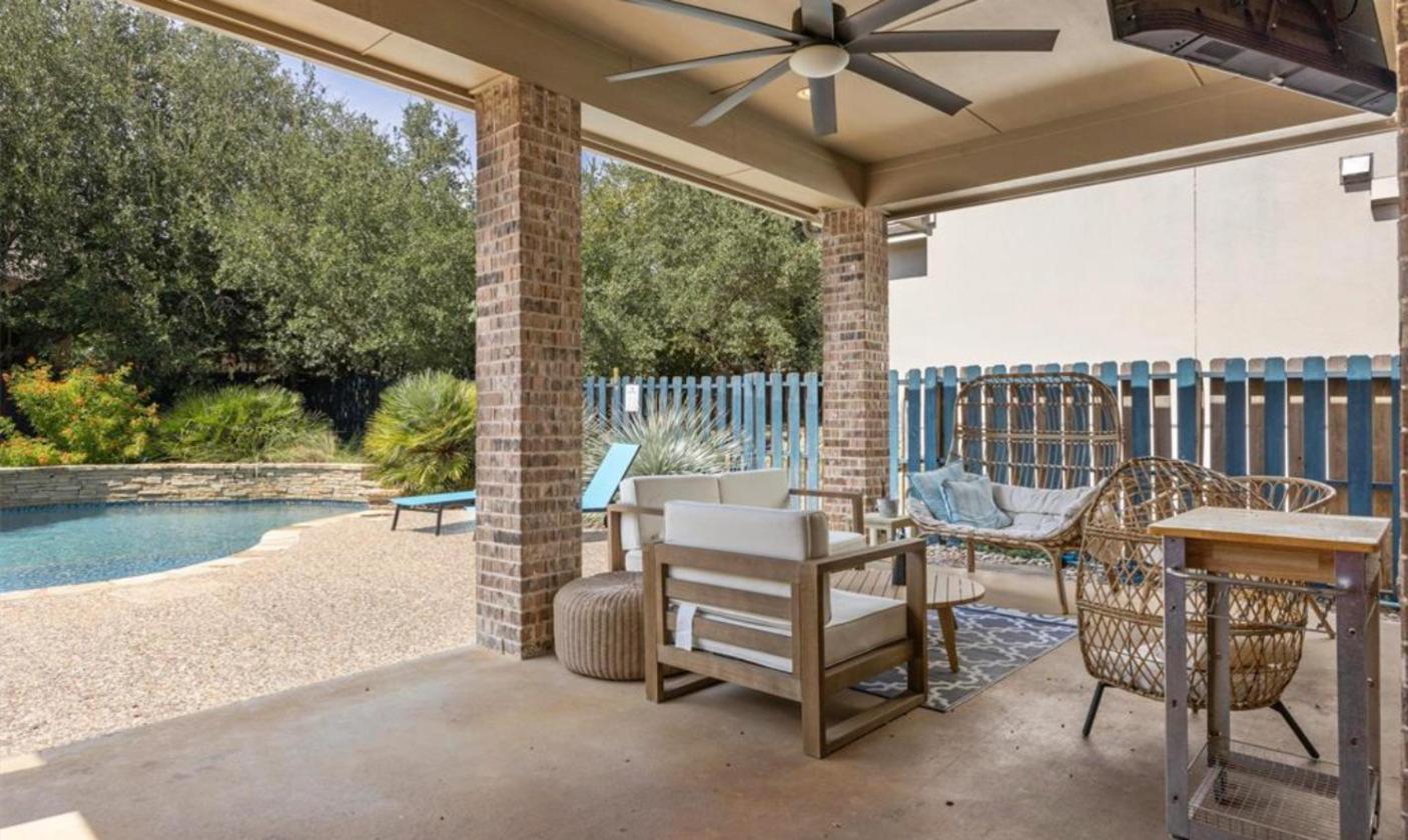 Covered patio with outdoor seating next to the pool at 17312 Wildrye Dr, Rocky Creek Ranch