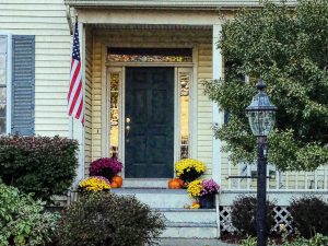 blue front door in yellow house with U.S.A. flag