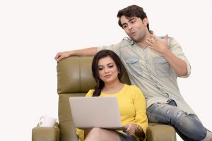couple looking at a laptop while sitting in a big chair