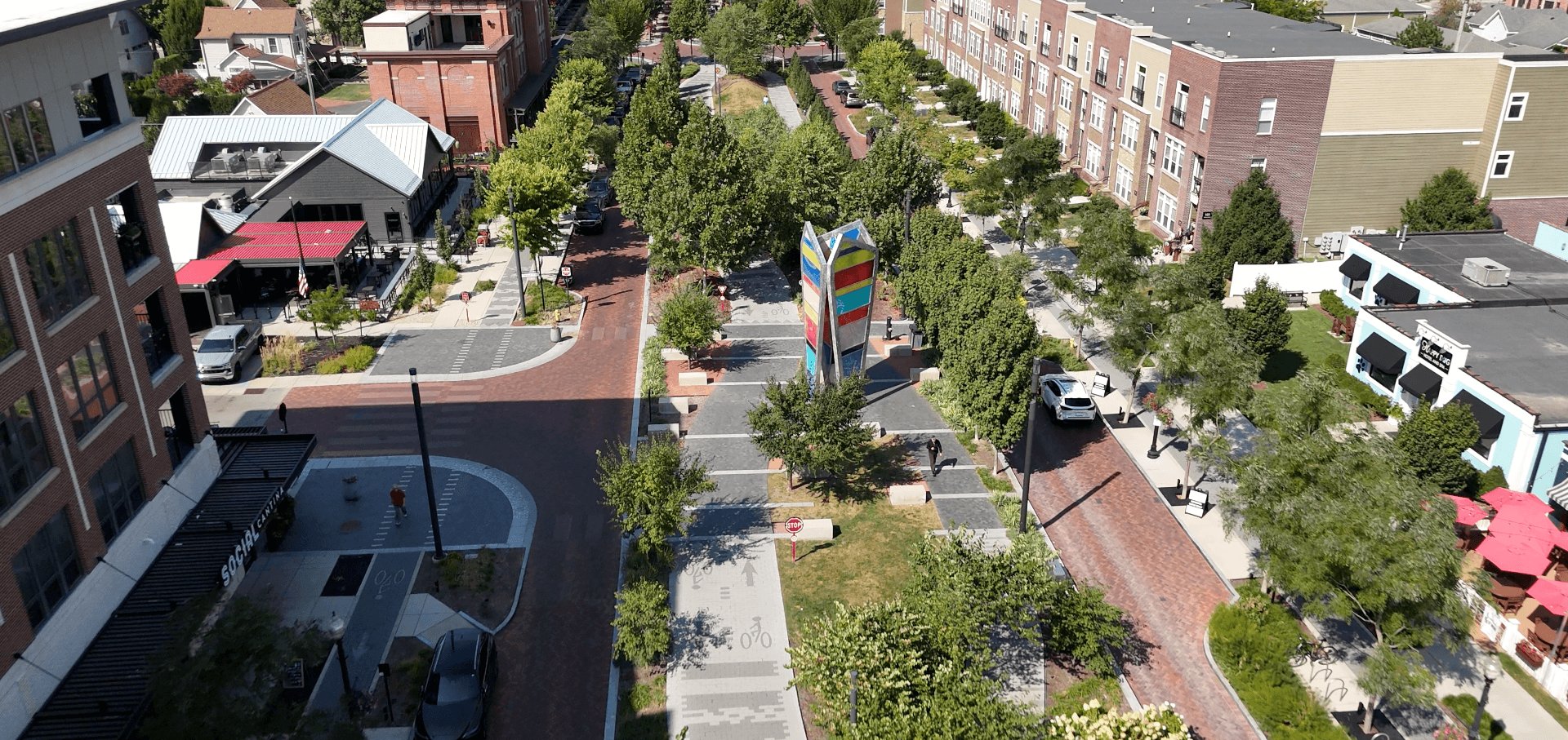 Aerial view of downtown Carmel, Indiana, featuring the colorful civic plaza, tree-lined walkways, and surrounding mixed-use buildings.