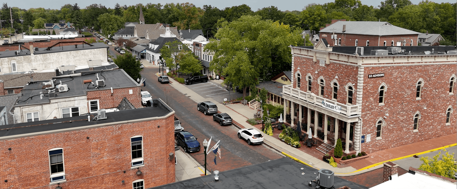Aerial view of downtown Zionsville, Indiana, featuring brick streets, historic buildings, and tree-lined sidewalks.