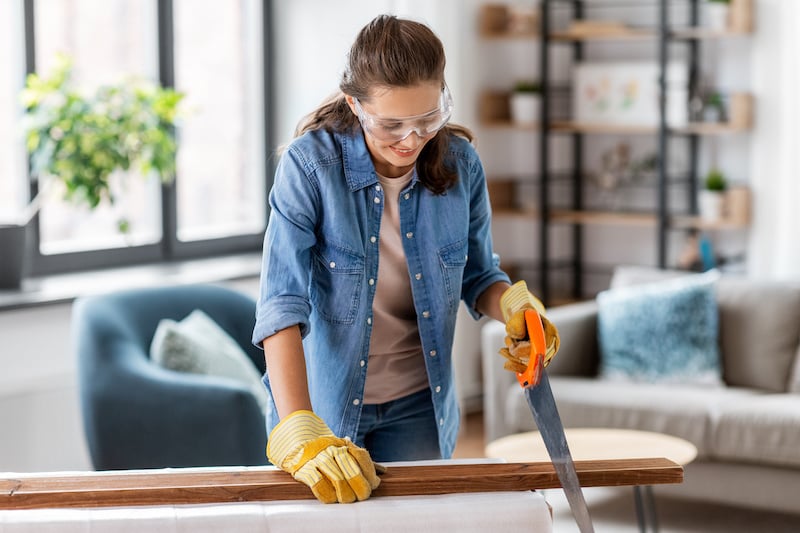 woman with saw sawing wooden board at home