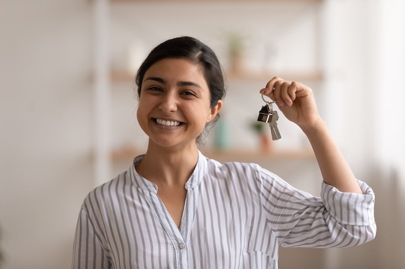 Young mixed race woman proud homeowner showing keys of flat