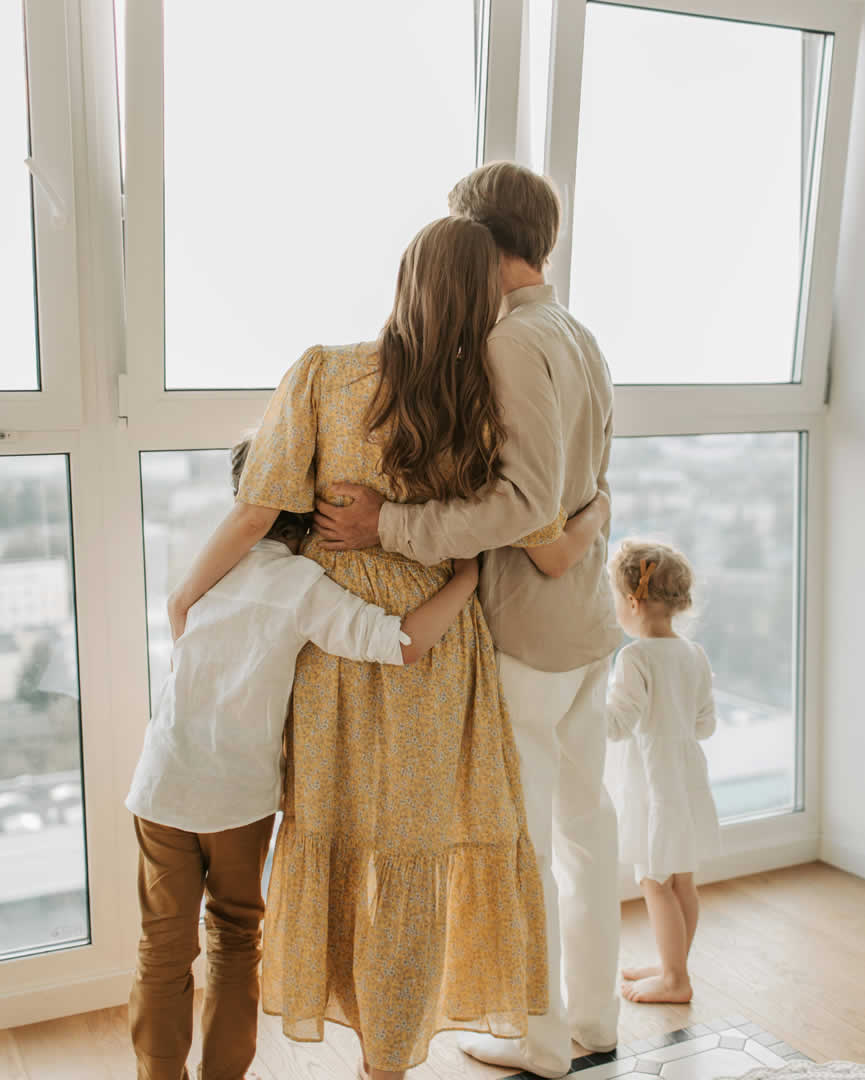 A family embracing as they look out a bright window