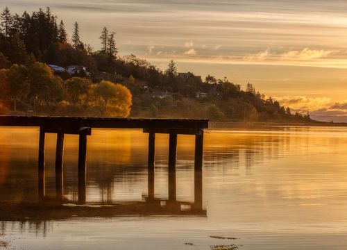 Tranquil lake with a wooden pier and sunset reflection in Comox, BC