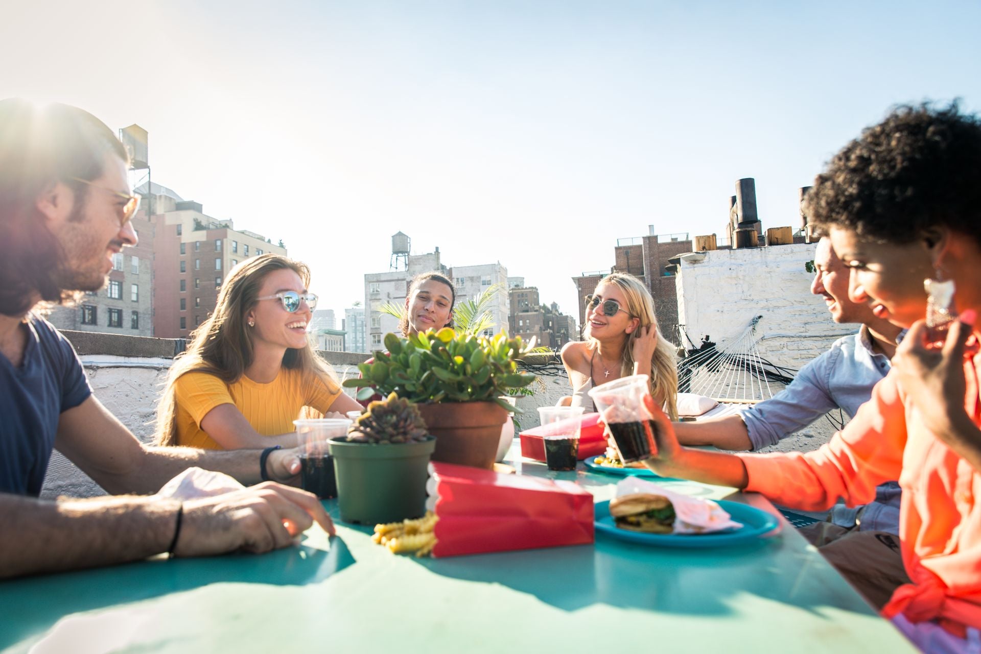 Young happy multiracial people having a barbecue dinner on a rooftop in New York - Group of multiethnicfriends having party and having fun on apartment terrace