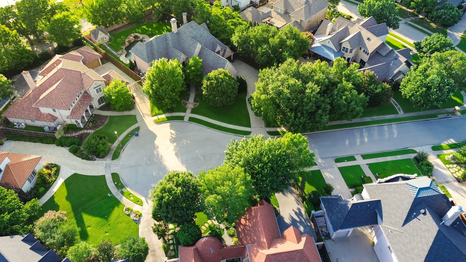 Cul-de-sac dead end street in upscale suburbs Dallas residential neighborhood expensive two-story mansion houses lush greenery trees, well-trimmed front yard landscape, Texas, aerial view. USA