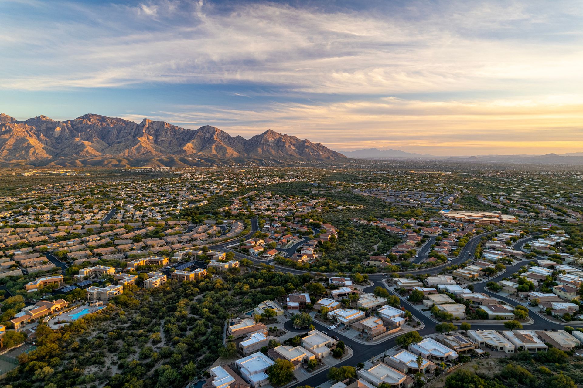 Oro Valley, Arizona Experience a stunning aerial sunset view showcasing the majestic mountains bathed in warm hues of orange and pink.