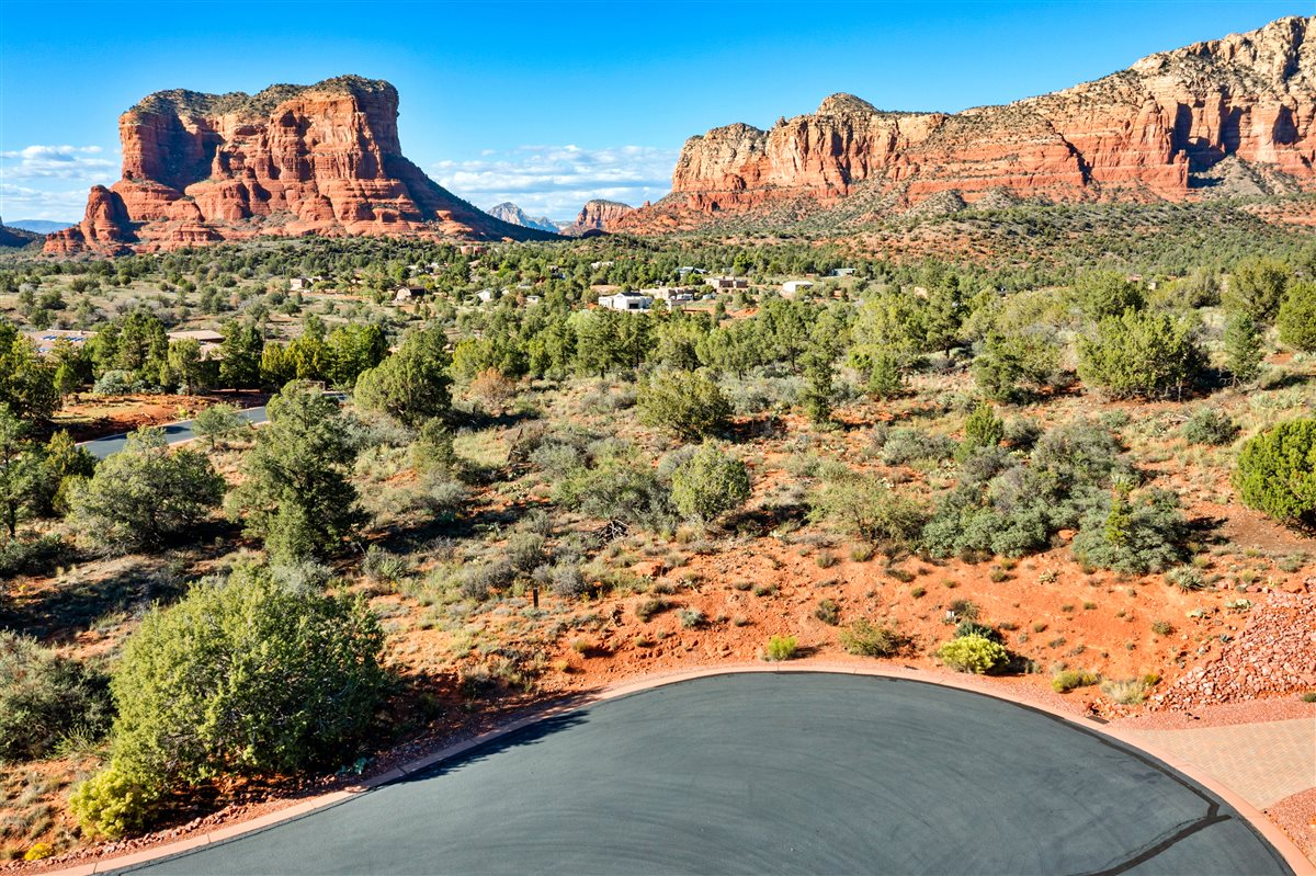Panoramic Sedona red rock views with desert landscape, natural greenery, and luxury homes surrounded by scenic mountains
