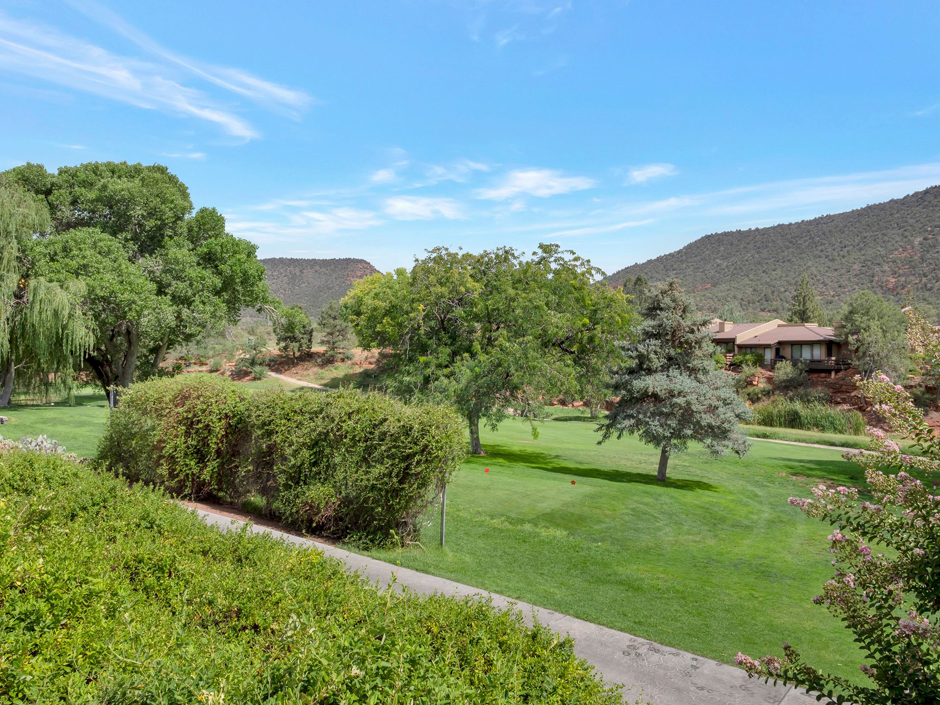 Sedona golf course community views with green landscape, mature trees, and surrounding desert mountains