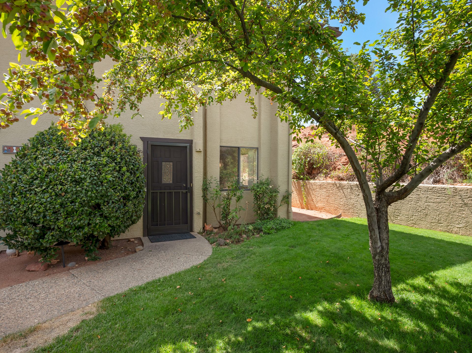 Sedona home entrance surrounded by mature trees, landscaped garden, and peaceful outdoor setting