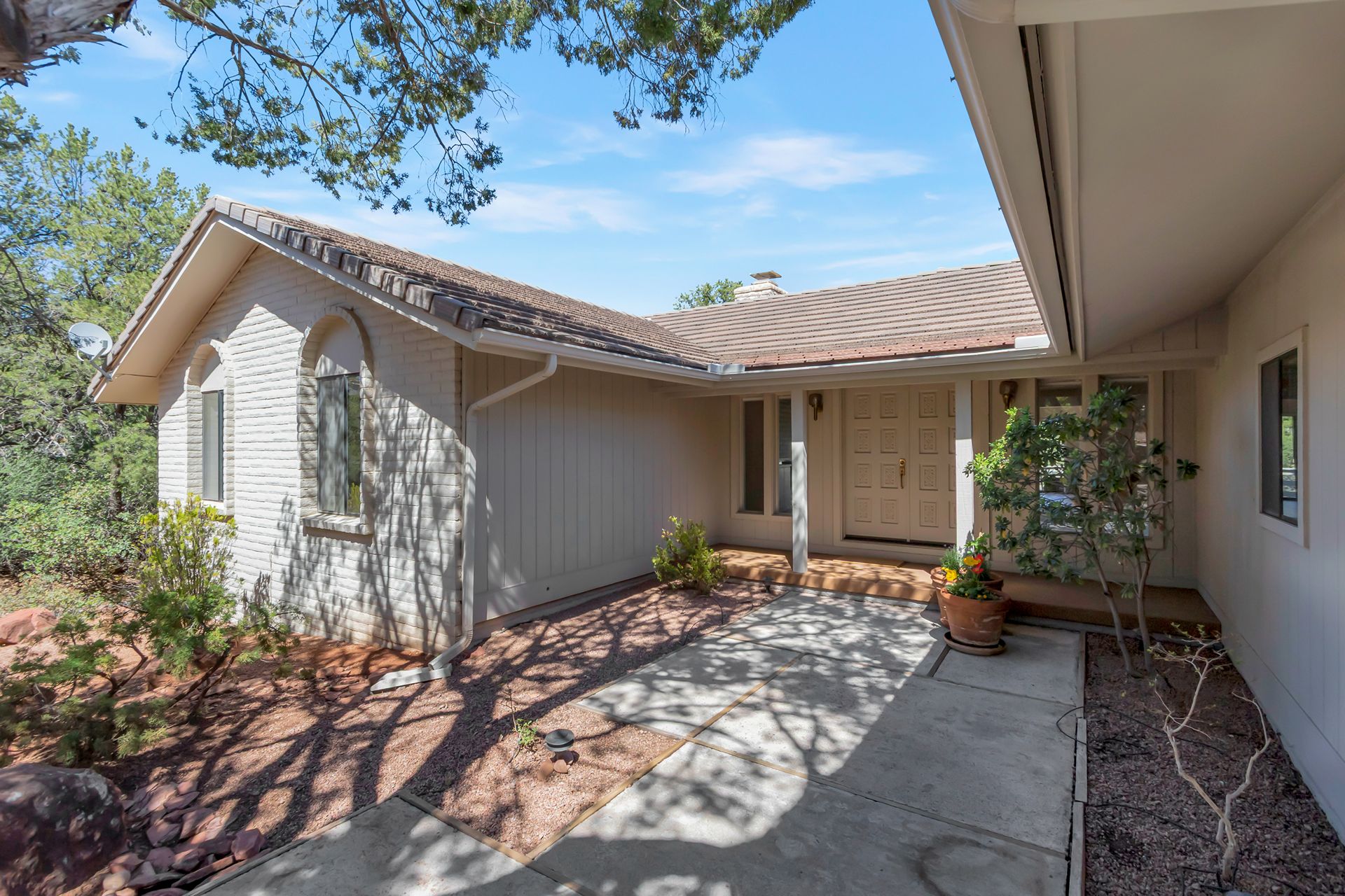 Sedona home exterior with landscaped entry, desert surroundings, and Southwestern architectural details
