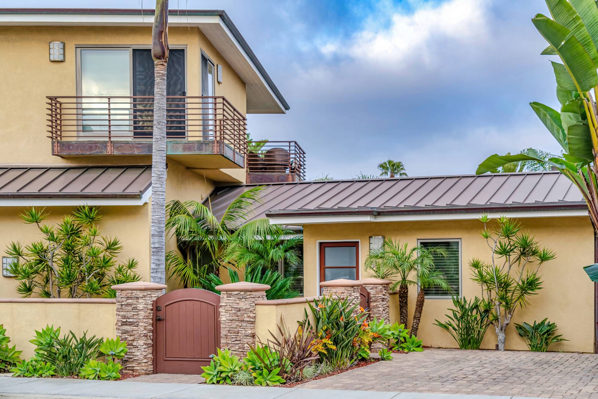Home in San Diego California with arched wooden gate against clouds and blue sky