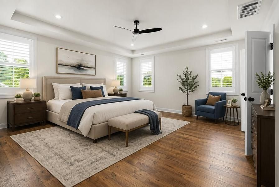 Staged bedroom with hardwood floors, seating area and natural light