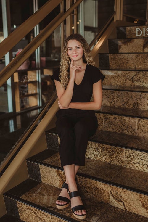 Birdee Cramer, Team member sitting on a golden stair